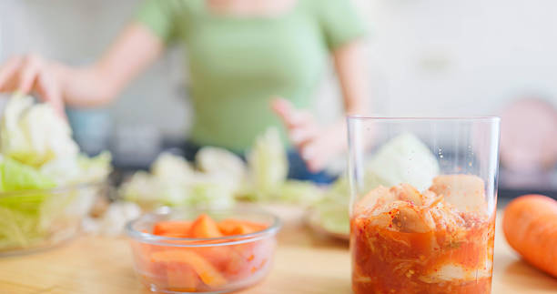 closeup Asian woman prepares cutting fresh cabbage for kimchi extending its shelf life through fermentation in her home kitchen - this traditional method helps minimize waste and supports sustainable food practices
