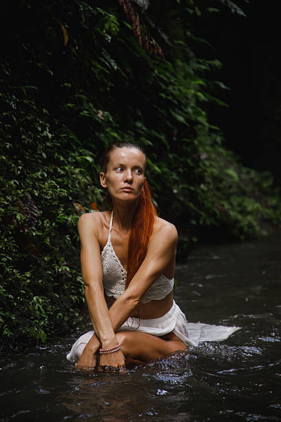 istock A serene woman sitting in a tranquil forest stream surrounded by lush foliage 2234126795
