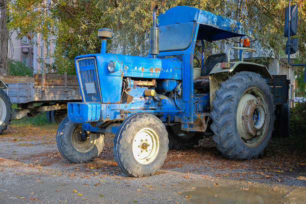 A Caucasian man in his 30s drives a tractor on his family's farm in rural Oregon while holding his elementary age daughter and preschool age son on his lap.