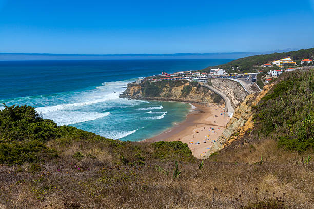 istock A stunning coastal panorama with turquoise waves crashing onto a sandy beach, framed by cliffs, greenery 2234128686