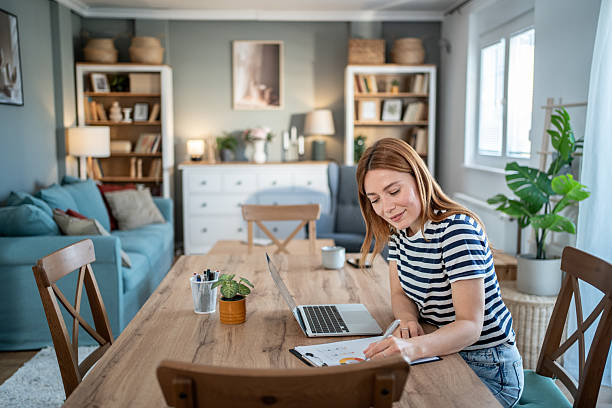 istock Young woman working from home on a laptop and taking notes 2234131518