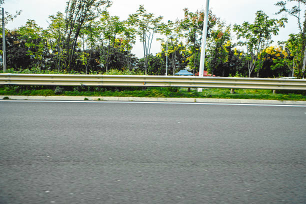 An empty S-shaped asphalt road winds sharply through a rural landscape, marked by white boundary lines and red-and-white chevron directional signs under a gloomy overcast sky. This transportation scene illustrates concepts of driving safety, navigating dangerous turns, and rural infrastructure during the late autumn or winter season.