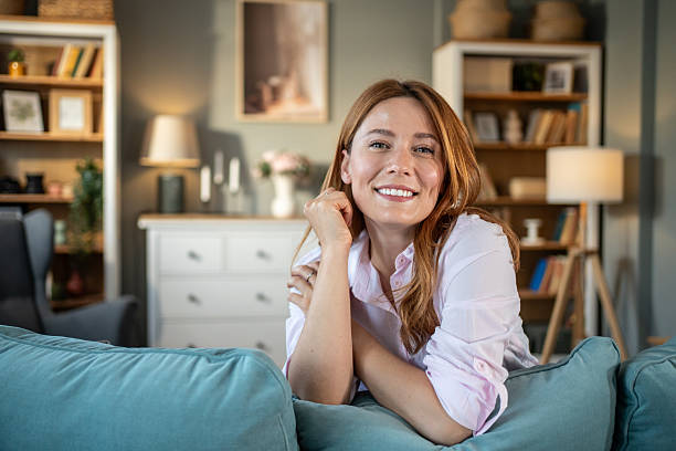 istock Young woman smiling and relaxing on sofa at home 2234134095