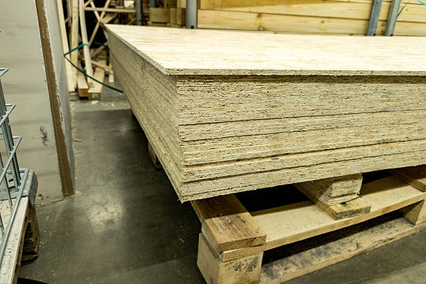 istock Large stack of engineered wood panels on a wooden pallet in a warehouse during daylight hours, highlighting the smooth surface and edges of the material 2234135217