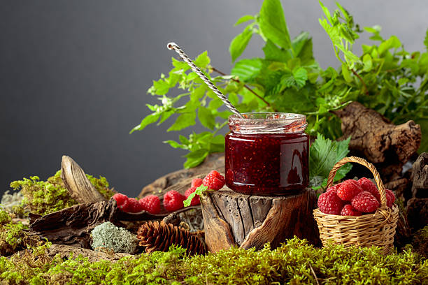 A jar of raspberry jam with fresh berries in small basket in the forest. A concept of healthy, eco-friendly food.