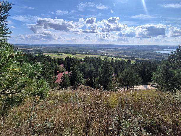 Landscape with a view of a meadow, forest and sky with clouds. The Volga River is visible in the distance.