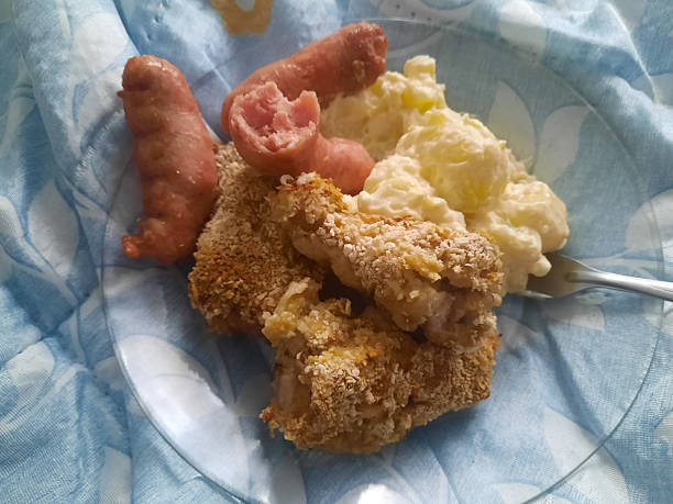 Fried sausages, mashed potatoes, and breaded chicken on a plate with blue napkin