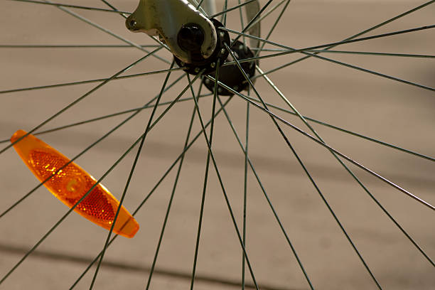 Detailed view of a bicycle wheel showcasing spokes and an orange reflective safety indicator, emphasizing cycling safety and equipment.