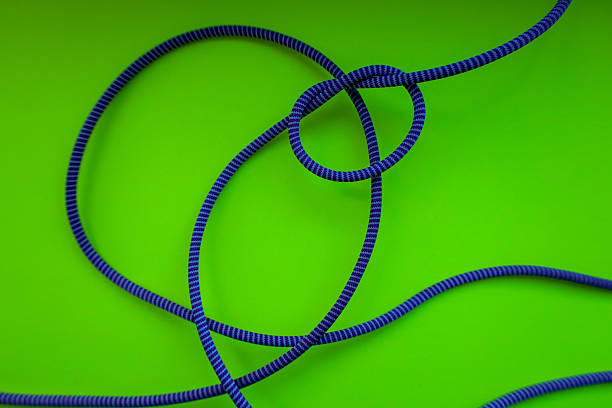 istock A blue-purple rope with a knot lies on a bright green background. The light and shadow pattern highlights the rope's texture and adds volume to the image. This abstract shot creates a sense of visual dynamics and graphic composition. 2234153046