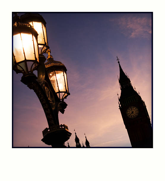 Lights illuminating Big Ben and Westminster Bridge at dusk in summer.