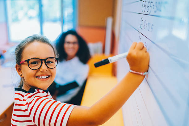 istock Schoolgirl writing on whiteboard in classroom 2234153566