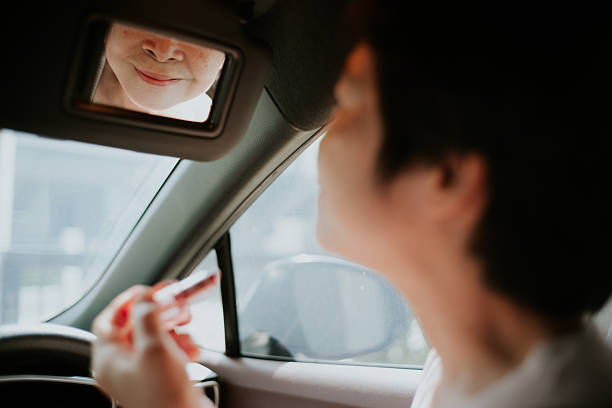 istock Mature woman applying lipstick in car. 2234154708
