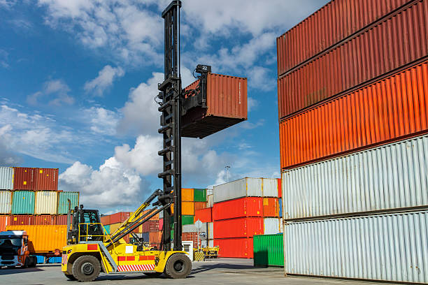 istock Crane lifting up container in yard. The loading truck is moving the freight container to the yard. 2234157633