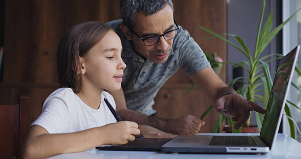 istock Father teaching his child daughter to draw digital pictures using graphics tablet, digitized pen and laptop computer 2234157735