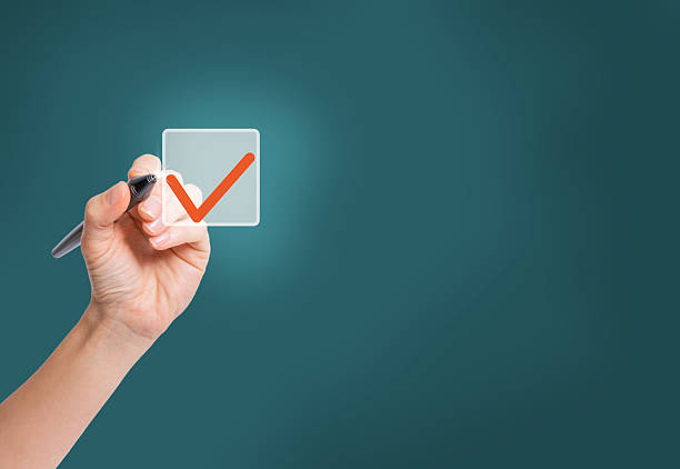 A woman's hand with a pen, marking the correct option with a tick. Checklist concept, checking boxes with red marker, copy space.