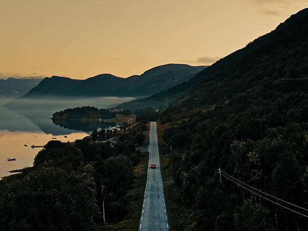 istock lonely car drive in dusk on a mountain road with deep forest shot from back red tail lights 2234159420