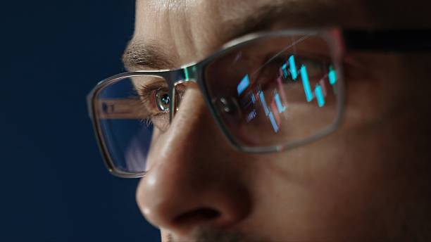 istock stock market charts reflecting in traders glasses while he analyzing crypto 2234162377