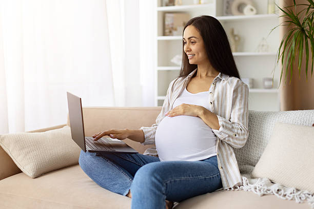 istock Smiling pregnant woman using laptop at home while holding belly 2234174595