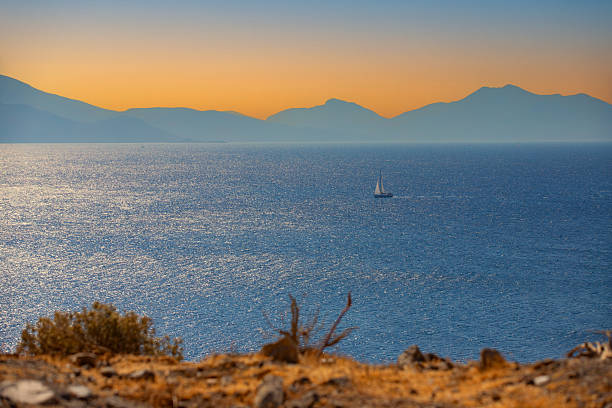 Sunset over the sea with mountain silhouettes and lush vegetation on the Greek island of Kos
