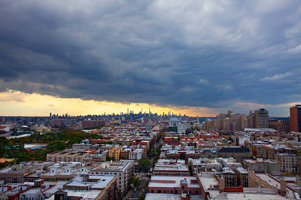 A sweeping aerial view of Manhattan's dense skyline at sunset, with dramatic clouds and golden light over the river. Captures urban energy, scale, and the vibrant mood of New York City. view from empire state building