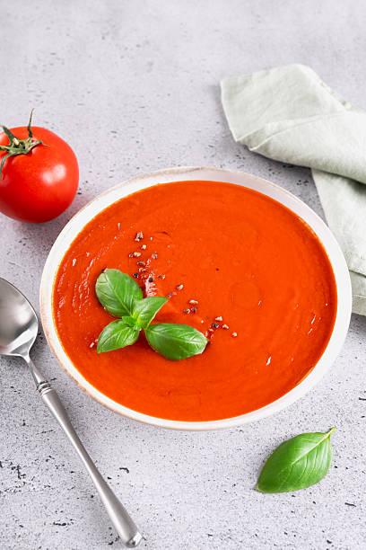 istock Vegetarian tomato cream soup with fresh basil on a gray background. 2234180552