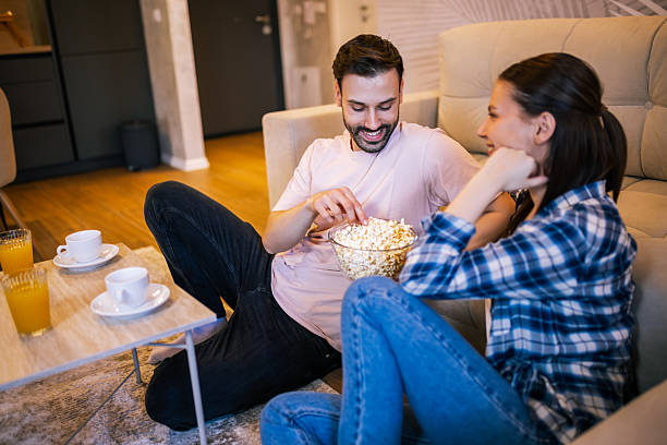 istock Young couple smiling while watching TV at home 2234183983