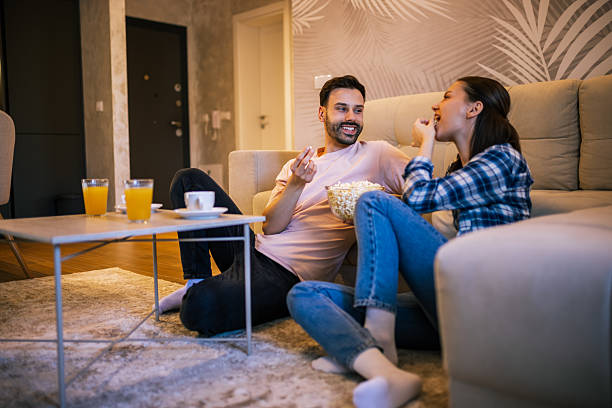 istock Young couple smiling while watching TV at home 2234184098
