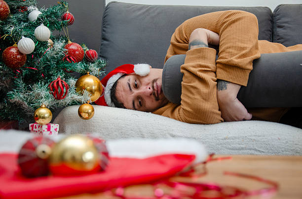 istock Crying and feeling depressed during the holidays. Abandoned and lonely. Sad young man lying on the couch and crying alone at home during Christmas. 2234192070