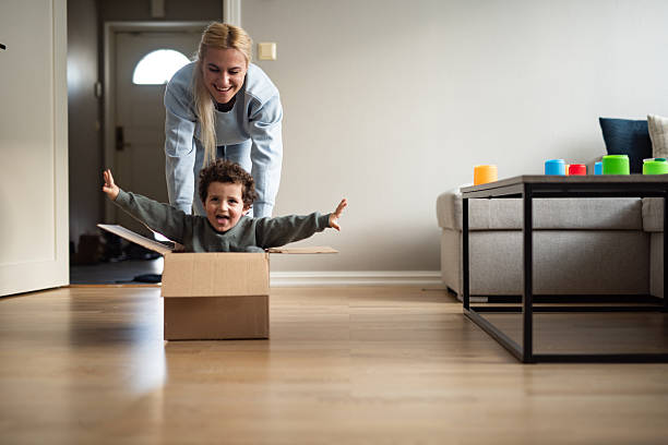 istock Happy mother and smiling son playing with cardboard box at home. 2234192649
