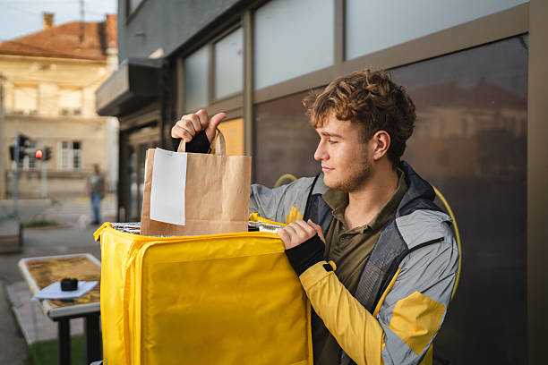 istock Deliveryman checking bag with thermal backpack in urban setting 2234194995