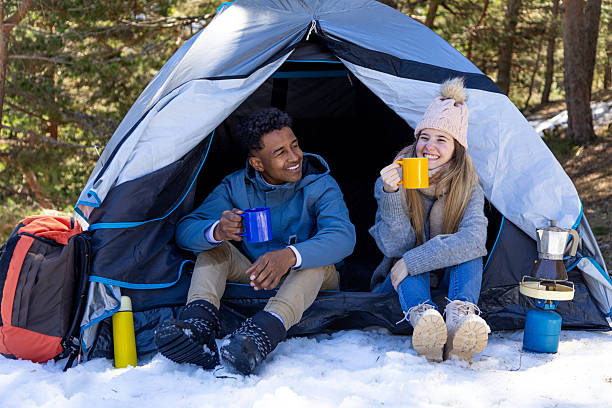 istock Happy hikers smiling and drinking hot beverage in tent during winter camping 2234195036