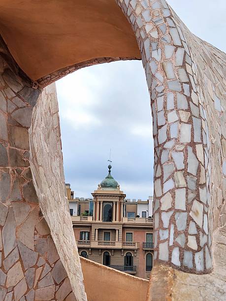 Gaudí’s arch framing another spire on the cityscape in Barcelona, Spain - ornate yet modernist, framing something equally monumental