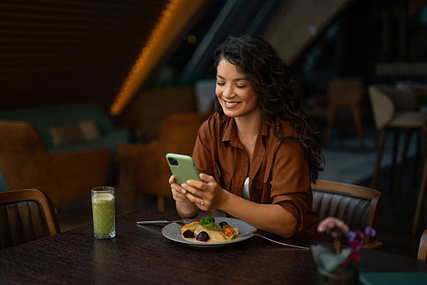 istock Woman eating lunch and using phone in a hotel restaurant. 2234223494