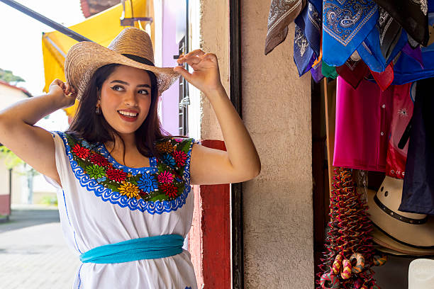 Mexican woman with flower headdress holding a mariachi hat. Woman with sombrero, white background.
