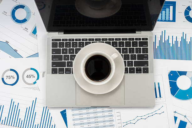 istock Office desk table with laptop, cup of coffee and financial chart. 2234224443