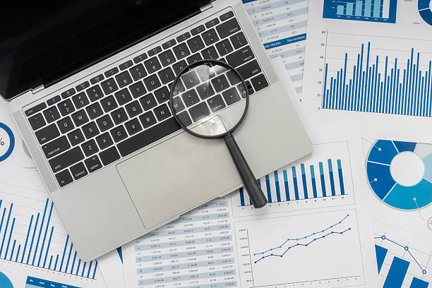 istock Office desk table with laptop, magnifying glass and financial chart. 2234224446