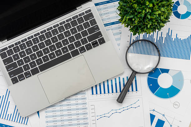 istock Office desk table with laptop, magnifying glass and financial chart. 2234224462
