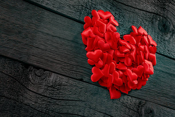 istock Red Heart Shaped Silk Decorations Against Rustic Wooden Background 2234226454