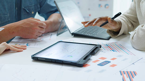 istock Close up Diverse Collaborative Business people meeting with Digital Devices computer brainstorming the financial report paperwork document analyzing data  planning strategies displays a graph  chart in a modern business technology overworked late at night 2234227901