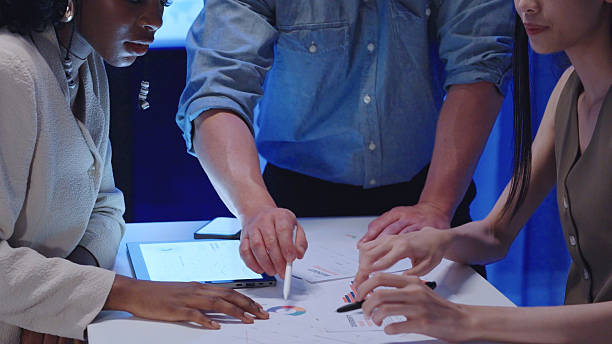 istock Close up Diverse Collaborative Business people meeting with Digital Devices computer brainstorming the financial report paperwork document analyzing data or planning strategies displays a graph or chart in a modern business technology overworked late at n 2234227903