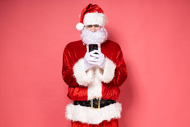 istock Santa Claus with a phone on a pink background. 2234229726