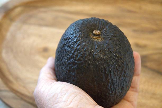 istock Single avocado on wooden table with hand 2234233107