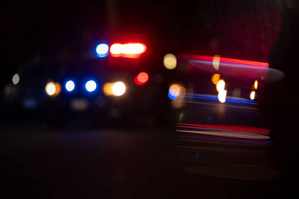 Abstracted view of police lights on a city street at night with lens flare.
