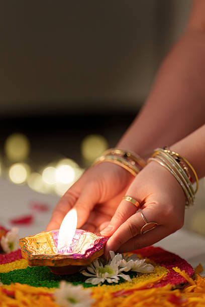istock Hands Placing Diwali Candle on Colorful Rangoli 2234234250
