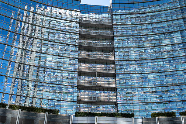 Milan, Italy, March 23, 2024: Modern glass facade with curved architecture and reflections in downtown Milan business district, editorial image