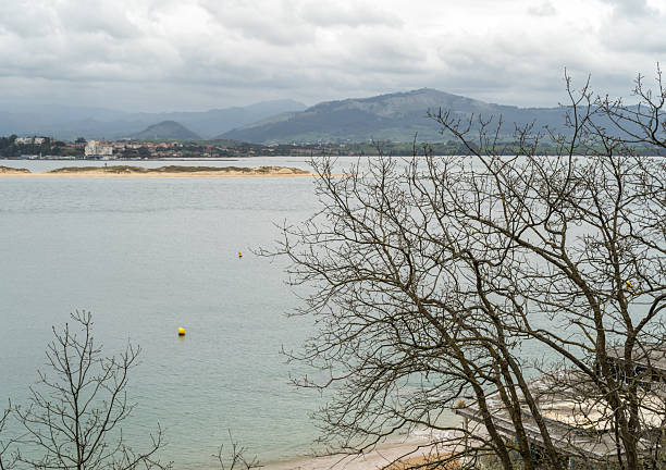 Santander, Spain, March 25, 2024: Abandoned beach building with graffiti on Santander coast surrounded by bare trees and overcast sky, editorial image