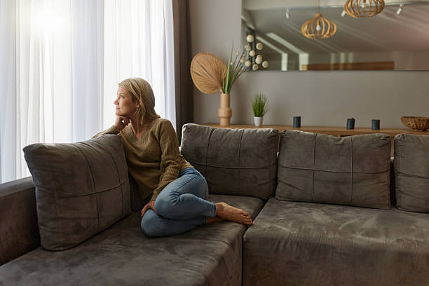 istock Smiling woman day dreaming on sofa at home. 2234246801