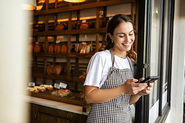 istock Successful female entrepreneur smiling in front of bakery using phone 2234249990