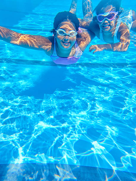 istock Two girls swimming underwater in bright pool. 2234251350