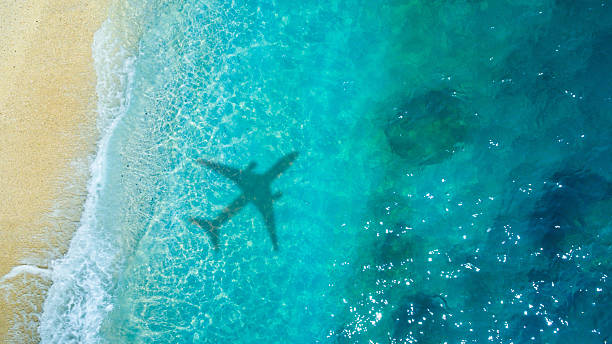 istock Airplane shadow over blue sea and foamy beach waves 2234252015